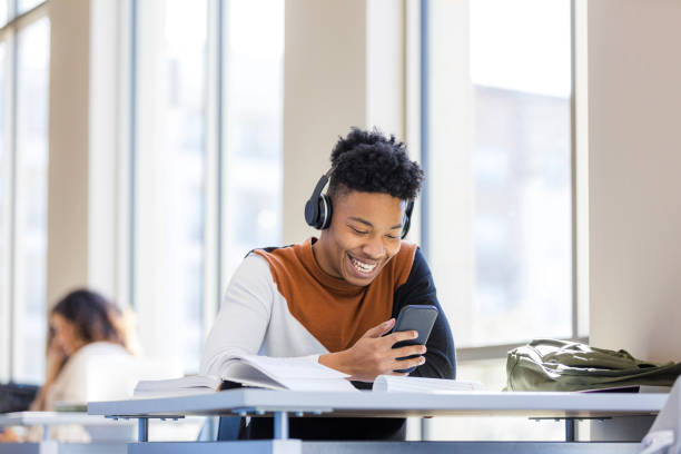 istock Happy young African American student using smartphone at desk 2199398201