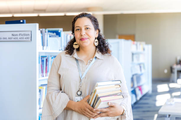 istock Portrait of a Smiling Librarian Holding Books in a Library 2199398214