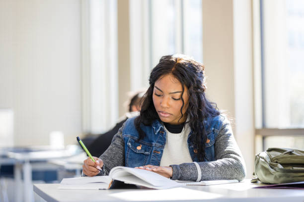istock Focused Young Woman Studying in Classroom, Pen and Book 2199398217