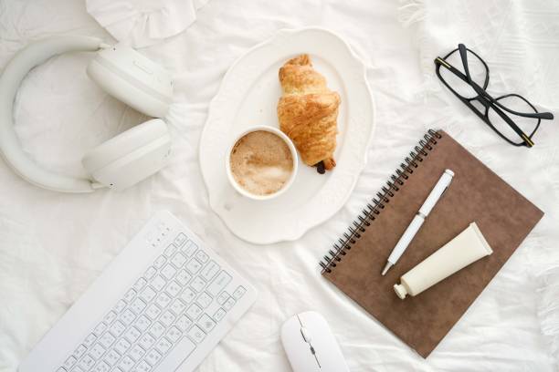istock A serene workspace with coffee, a croissant, and essential tech items - keyboard, headphones, notebook to boost productivity and creativity on white fabric background. 2199398694