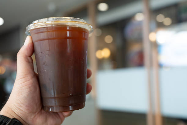 Hand holding a plastic cup of black coffee
