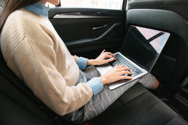 istock Woman using laptop in the back seat of a car 2199400548