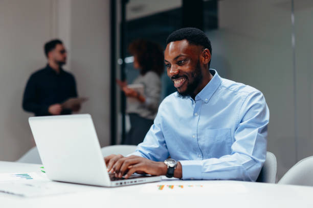 istock Young businessman smiling and working on laptop in modern office 2199400687