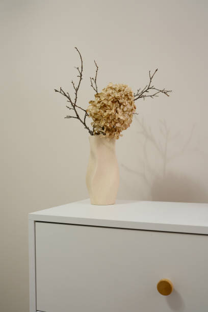 istock A chic and stylish vase with dry flowers on white table. 2199400710