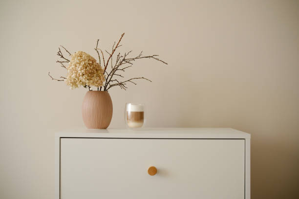 Stylish minimalist decor ideas using beautiful dried flowers, exquisite coffee on white dresser. High quality photo