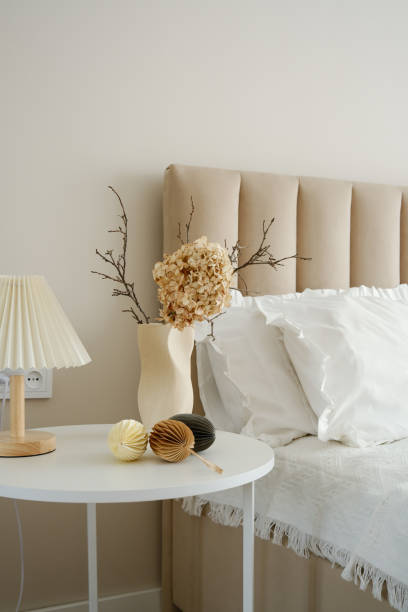 istock Elegant vase with dry branches and flower, easter eggs on white table near light bedside. 2199401531
