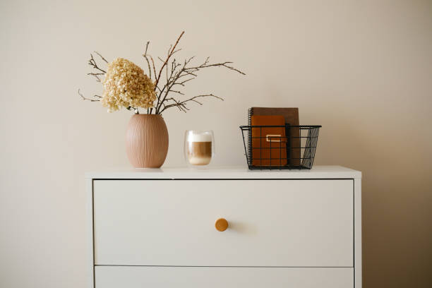 istock Stylish minimalist decor ideas using beautiful dried flowers, exquisite coffee, books in a basket on white dresser. 2199402272
