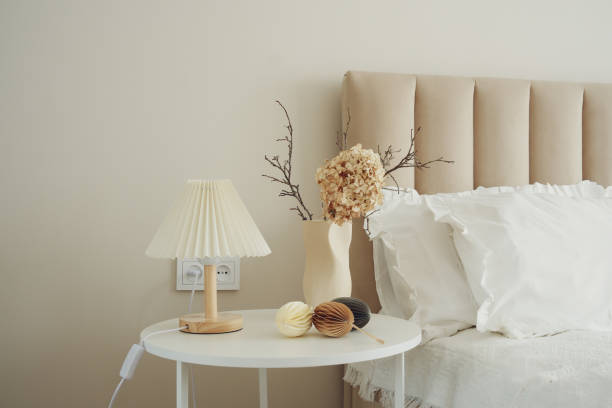istock Elegant vase with dry branches and flower, easter eggs on white table near light bedside. 2199402847