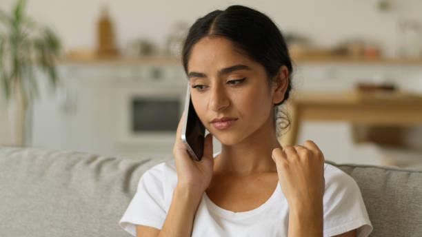 istock Emotional negative bad conversation distant quarrel conflict Indian woman talk call smartphone at home annoyed irritated Arabian girl female talking argue mobile phone at couch problem trouble angry 2199403328