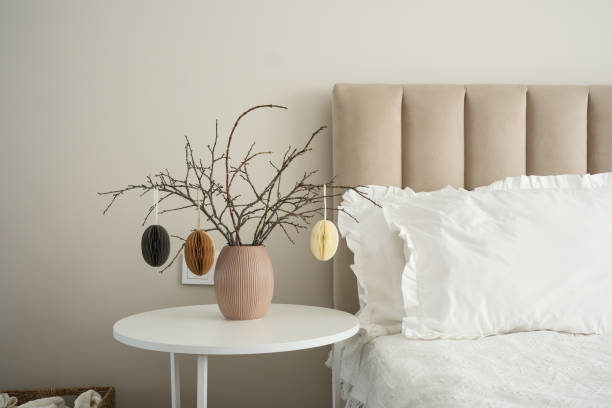 istock Elegant vase with dry branches, easter eggs on white table near light bedside. 2199403416