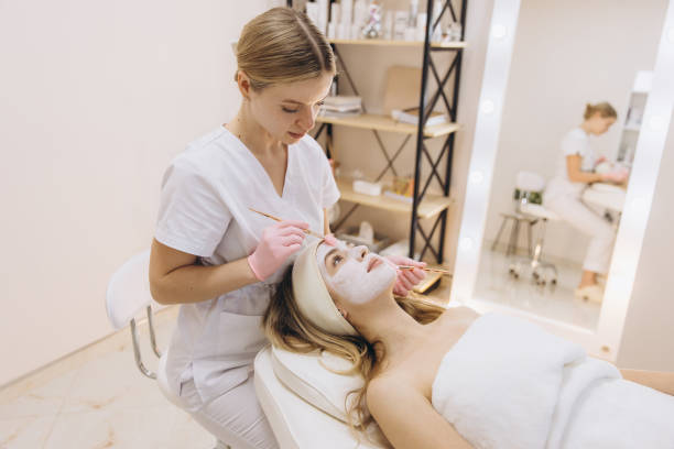 istock Cosmetologist skillfully applying a facial mask to a client in a relaxing spa setting, enhancing skin care and beauty through expert techniques 2199403942