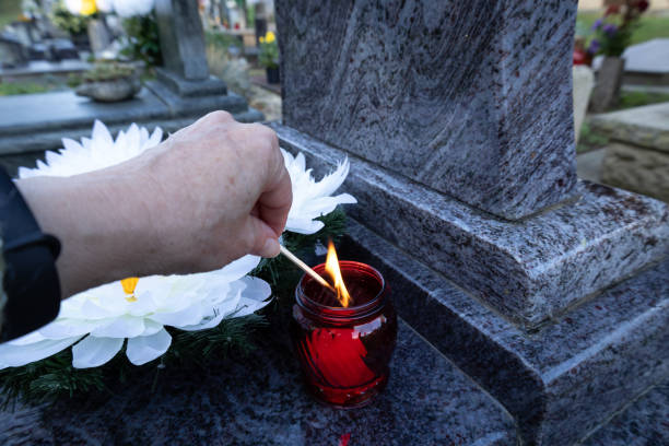 istock Hand lighting a red candle lantern at the cemetery with white flowers. 2199406267