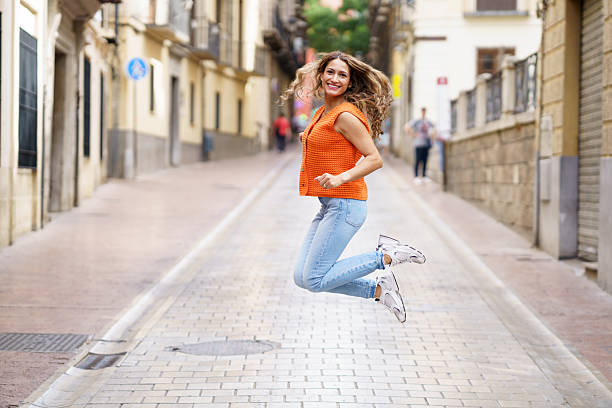 Latin woman jumping in the middle of street stock photo