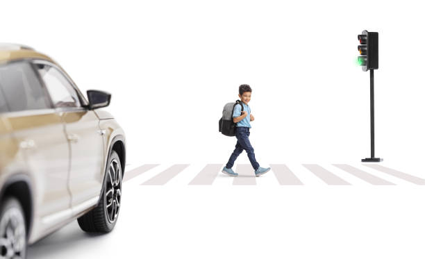 istock Boy with a backpack walking at a pedestrian zebra crossing and looking at a car 2199407977