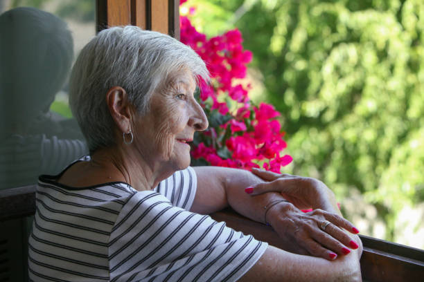 istock senior latino woman looking through the window 2199408737