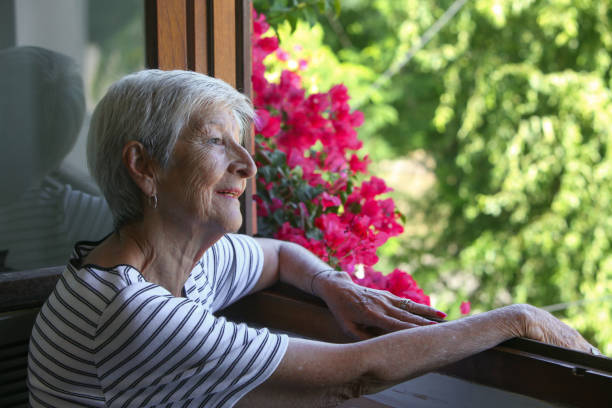 istock senior latino woman looking through the window 2199408773