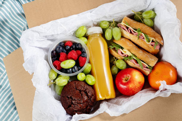 Ready prepared brunch box with sandwiches, fruits, berries and smoothie. Quick food to eat on the go or for lunch break, time saving ready to eat healthy meals, top view