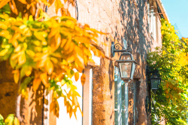 Charming cotswolds stone cottage with a hanging lantern and autumn leaves, bathed in warm sunlight