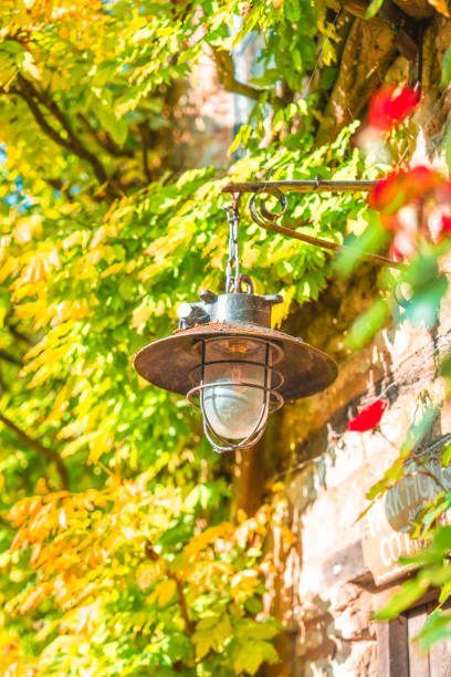 Vintage lantern hangs on a stone wall adorned with autumn leaves in the cotswolds, england