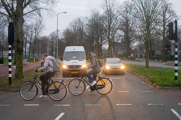 Two girls crossing a traffic light on a Dutch bicycle. North Brabant. Netherlands. December 12, 2024.