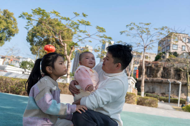 A young father is happily playing with his two daughters in the park