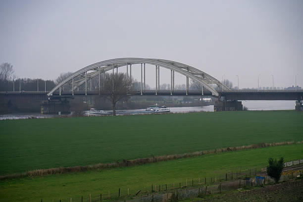 Barge sailing under a bridge on a canal in a country passage in winter. Netherlands. December 11, 2024.