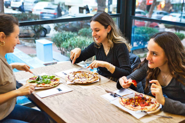 istock Mother and her daughters eating their pizzas at the restaurant. 2199419336