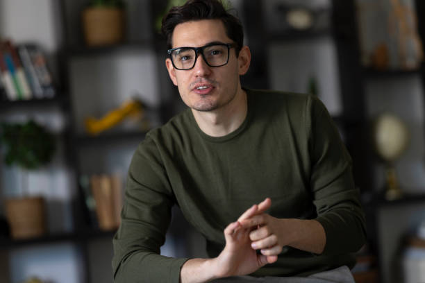 istock Young adult man gesturing with his hands while talking on a video call from his home office 2199421292