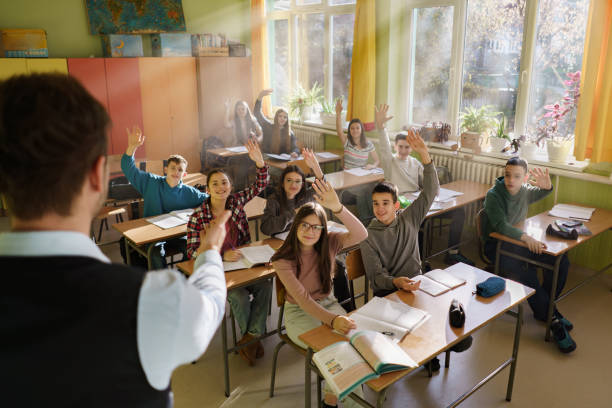 istock Smart children whit raised hands in the classroom 2199427402