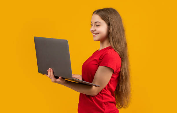 istock cheerful child with laptop on yellow background 2199428091