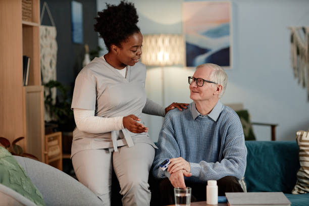 istock Black Female Caregiver Talking to Senior Man Testing Oxygen Level while Visiting Patient at Home 2199430688