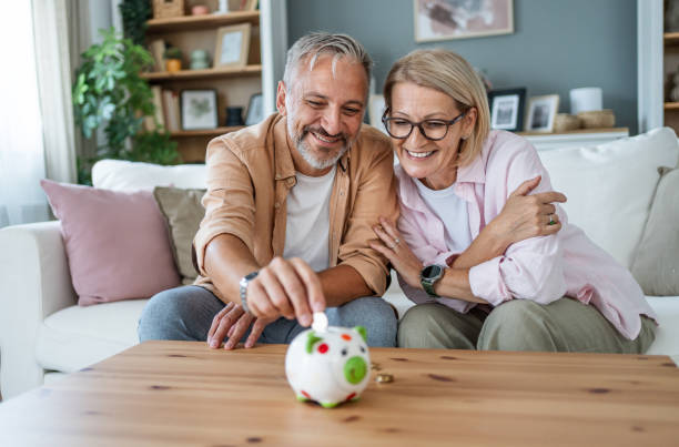 istock Mature couple inserting coins in a piggybank 2199430997