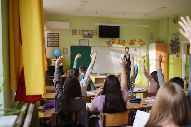 istock Children raising hands to answer the teacher's question 2199431006