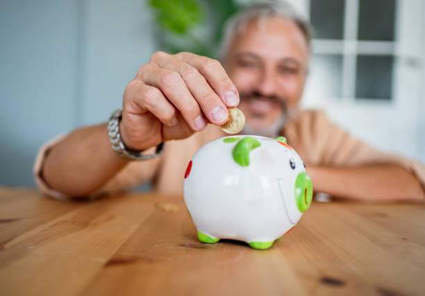 istock Man inserting coins in a piggybank 2199431722
