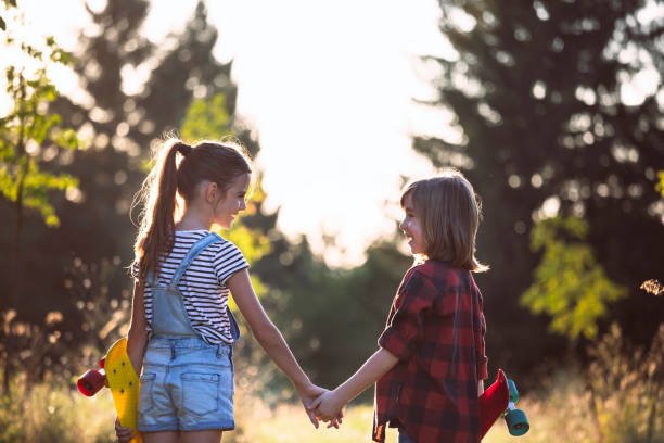 A boy and a girl are standing together in the park