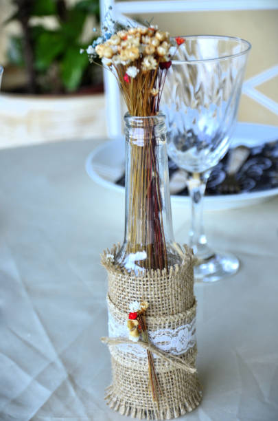 istock Bottle decorated with jute and small artificial flowers on party table 2199439843