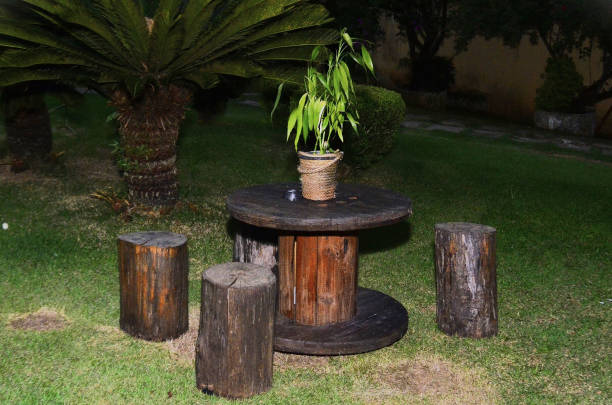 Wooden spool table and benches with tree trunks on lawn decorating garden