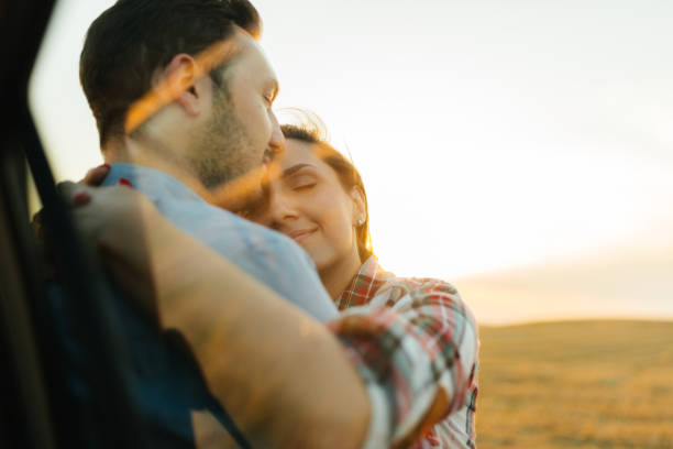 Close up of a happy couple hugging in the field, a young couple in love hugging in the green field, A man hugging his woman in a beautiful field