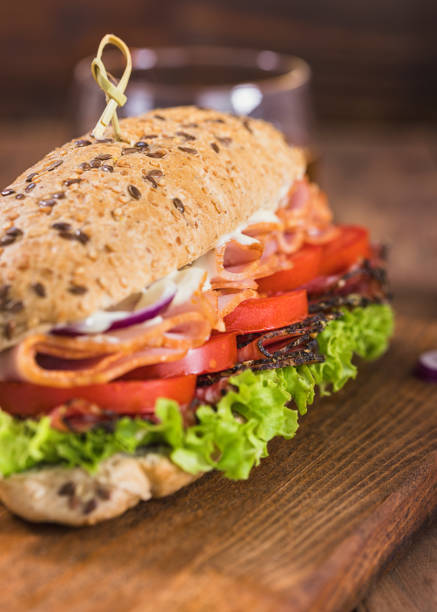 Toast with ham and a leaf of green lettuce poured with ketchup on a wooden background.