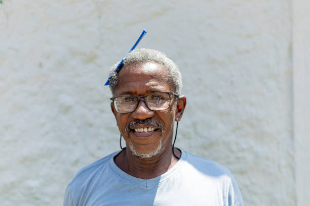 Handsome elderly black man using a blue fork comb in his hair. African man. African senior.