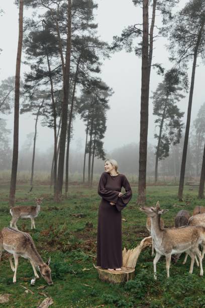 istock A woman in an elegant dress poses between a forest and wild deer, creating a harmonious and fairy-tale atmosphere. woman and deer symbolize the unity of man with nature, meekness and naturalness. 2199442323