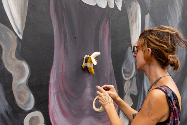 Young non-binary artist in front of its artwork on a mural - Buenos Aires - Argentina