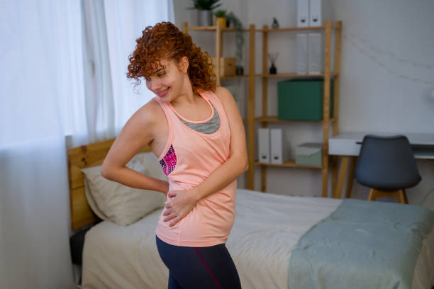 istock woman holding her lower back, suffering from back pain at home 2199448175