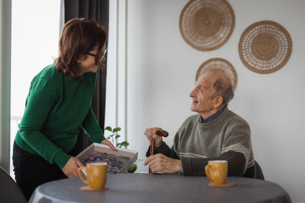 istock Elderly man getting a visit from volunteer in nursing home, playing puzzle 2199450040