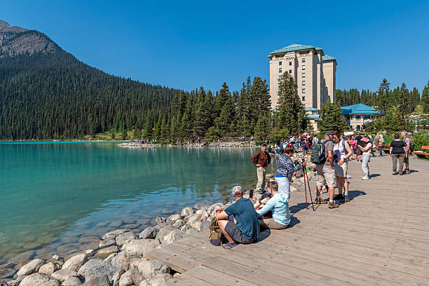 People hiking along Lake Louise with hotel in background, Banff national park, Alberta, Canada.