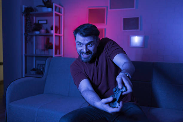istock Excited young man playing videogames at home at night 2199450509