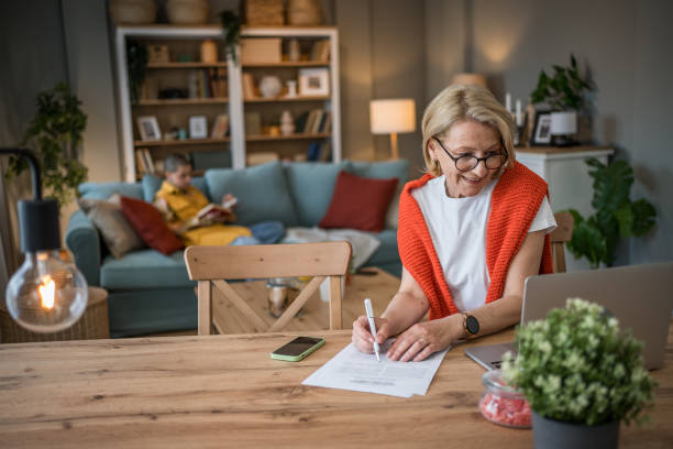 istock Senior woman working from home while granddaughter reads 2199459028