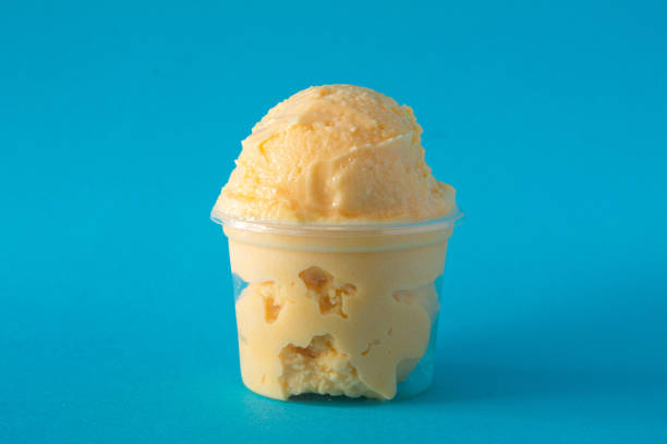 istock Delicious mango ice cream overflowing its plastic cup on vibrant blue background 2199460133