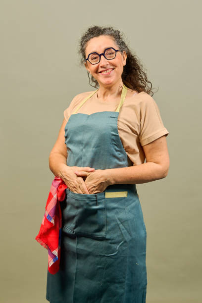 istock A woman wearing a blue apron and glasses is smiling 2199460389