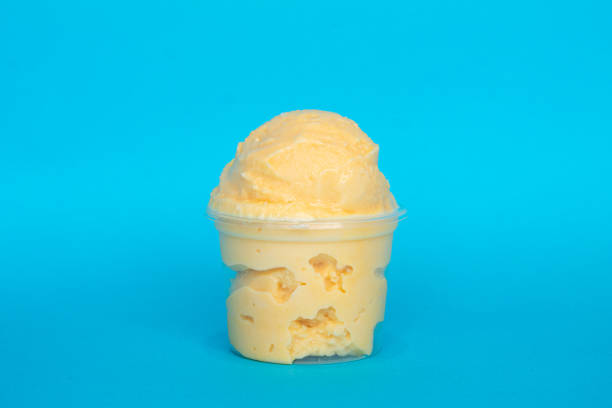 istock Mango ice cream overflowing in a plastic cup on a vibrant blue background 2199460582
